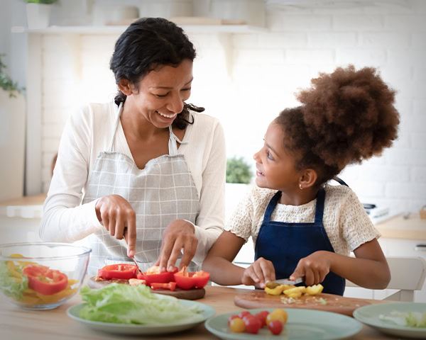 Lady and child in the kitchen cutting up vegetables